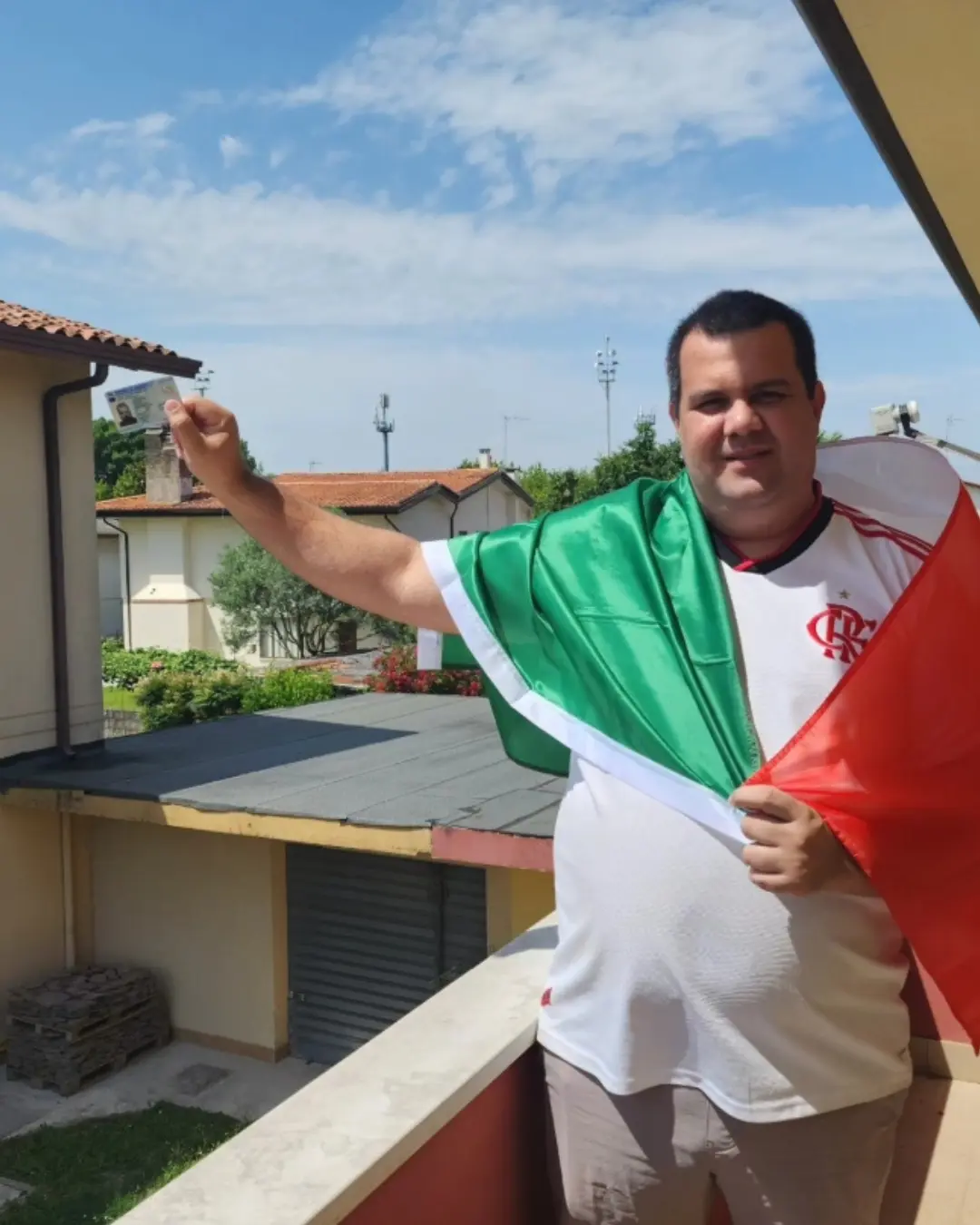Cliente de Speranza en un balcón, levantando el documento de identidad con la bandera de Italia