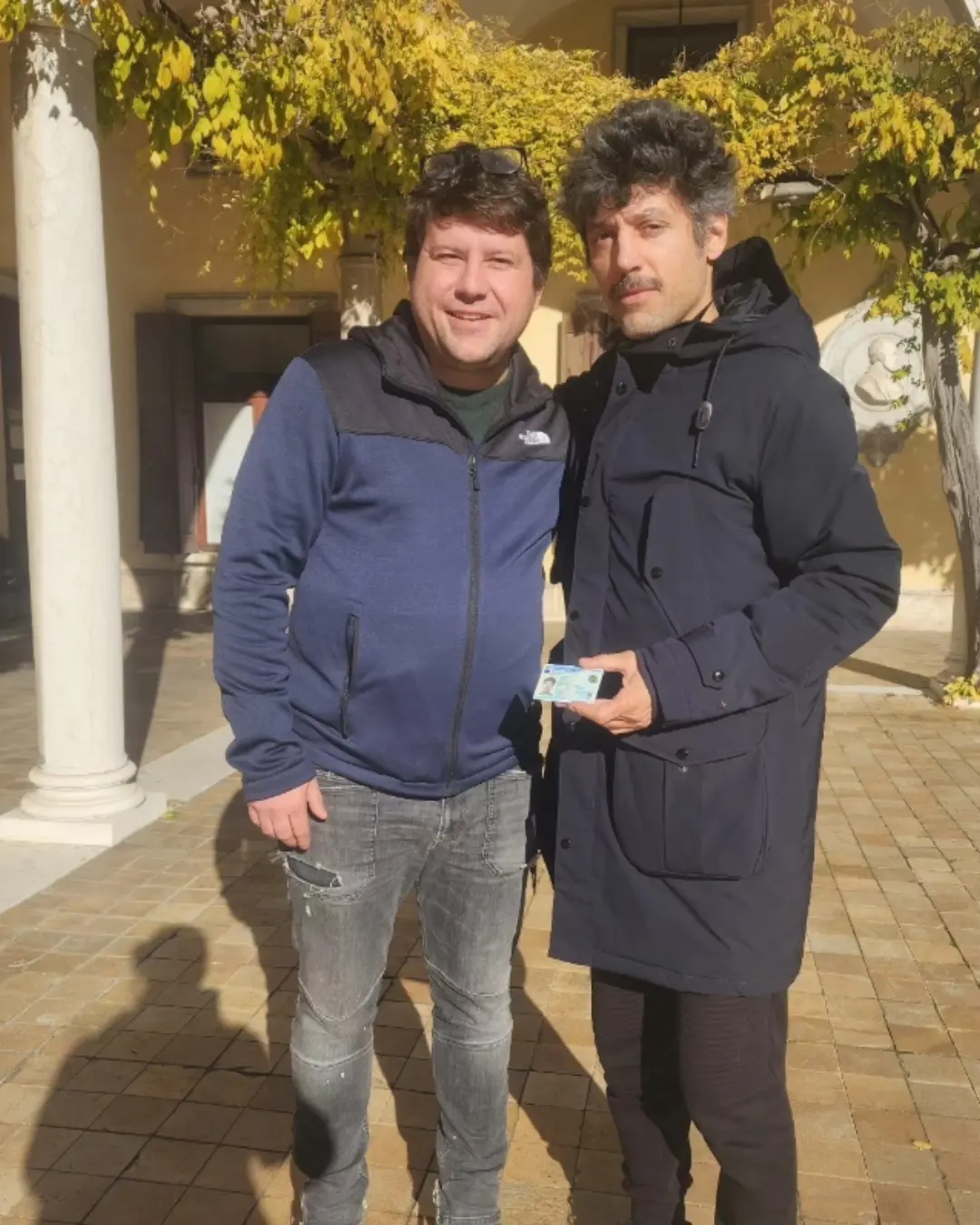 Dos clientes de Speranza posando juntos, uno con el documento de identidad italiano